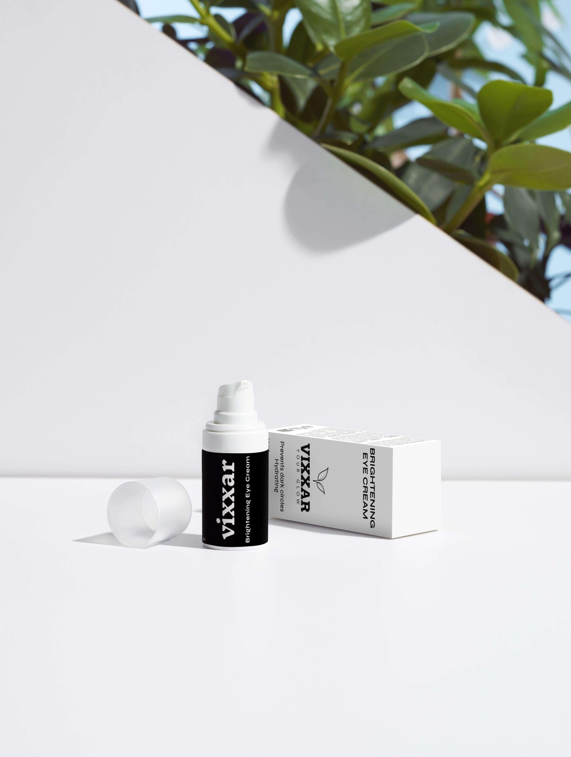 Vixxar Eye Brightener serum with packaging, surrounded by green plants, on a minimalist white background.