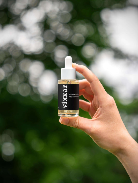 Vixxar AHA Peeling Concentrate held outdoors, part of the Ultimate Renewal Collection, for exfoliation and radiant skin.