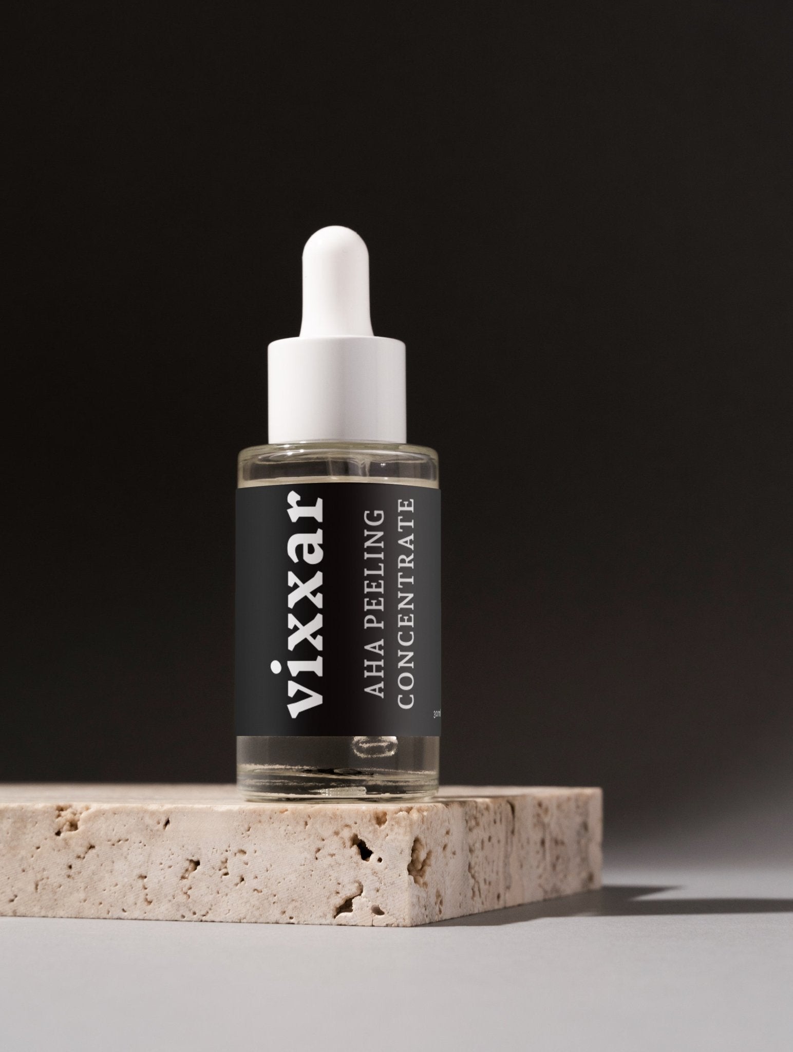 Bottle of AHA Peeling Concentrate on a stone platform with a black background