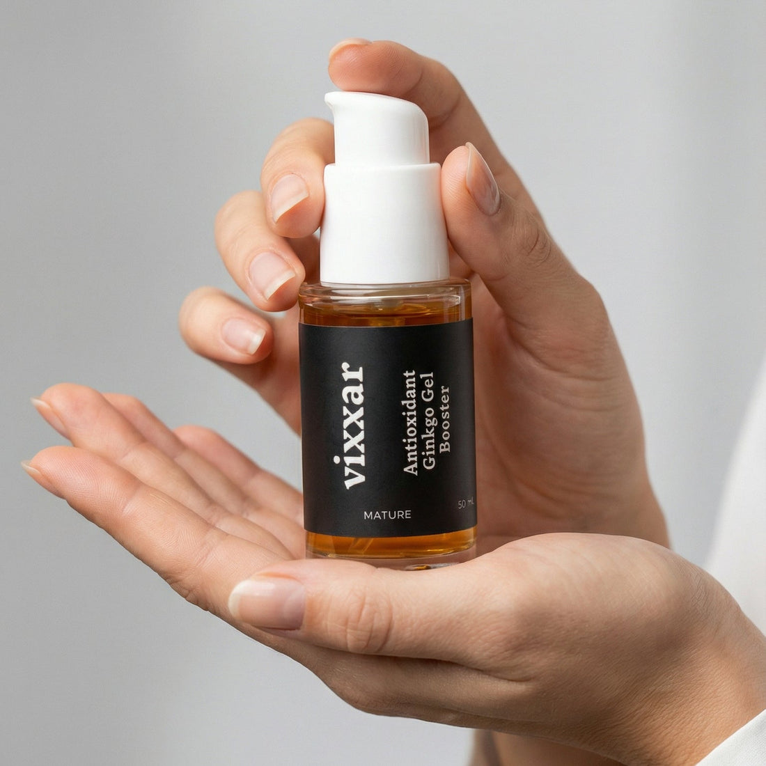 Hand holding a bottle of Vixxar product against a neutral background