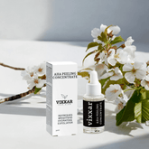 AHA Peeling Concentrate 30ml bottle with box, featuring lactic and hyaluronic acid, surrounded by white blossoms for skin glow and hydration.